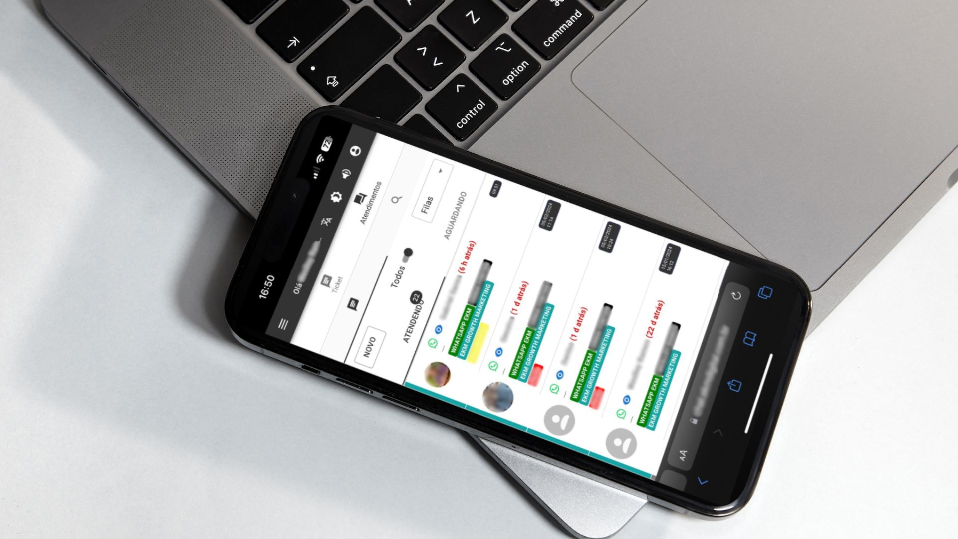 Um iphone sobre um macbook em uma mesa, mostrando a tela do EkmChat com todos os canais de atendimento centralizados.