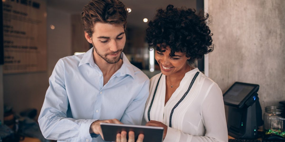 Duas pessoas olhando para um tablet debatendo resultados de marketing.